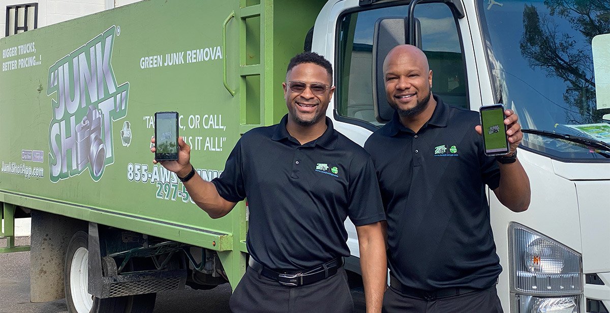 franchise owners holding app on phone in front of junk shot truck